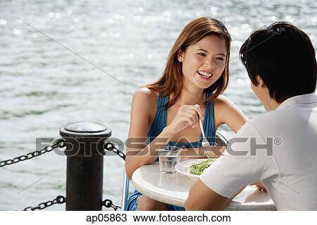 Stock Image - Couple sitting at outdoor cafe, having lunch. Fotosearch