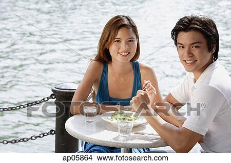 Picture - Couple sitting at outdoor cafe, looking at camera. Fotosearch