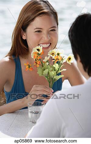 Couple sitting at outdoor cafe, woman holding flowers View Large Photo Image Stock Photo - Couple sitting at outdoor cafe, woman holding flowers. Fotosearch