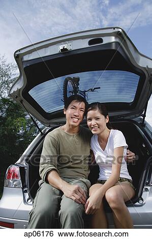 Couple sitting in boot of car, smiling at camera View Large Photo Image Stock Photograph - Couple sitting in boot of car, smiling at camera. Fotosearch