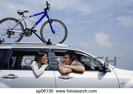 Couple sitting in car, leaning out of the windows, bicycle on the roof View Large Photo Image Stock Image - Couple sitting in car, leaning out of the windows, bicycle on the roof. Fotosearch