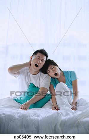 Couple sitting on bed, yawning View Large Photo Image Stock Photography - Couple sitting on bed, yawning. Fotosearch