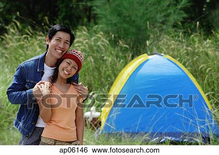 Couple smiling at camera, tent in the background View Large Photo Image Stock Photograph - Couple smiling at camera, tent in the background. Fotosearch