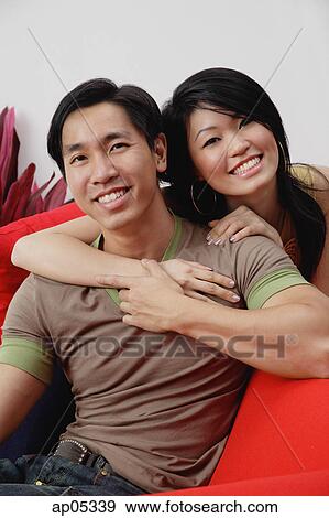 Couple smiling at camera, woman embracing man from behind View Large Photo Image Stock Photo - Couple smiling at camera, woman embracing man from behind. Fotosearch