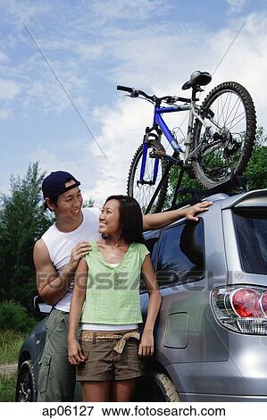 Couple standing next to SUV, looking at each other View Large Photo Image Stock Photo - Couple standing next to SUV, looking at each other. Fotosearch