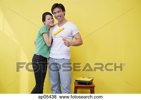 Couple standing together, man holding paint roller View Large Photo Image Stock Photo - Couple standing together, man holding paint roller. Fotosearch