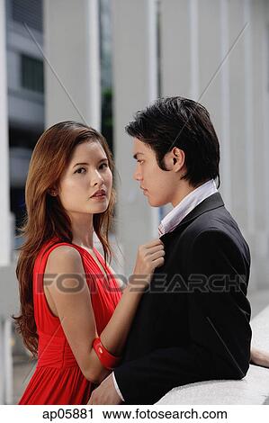 Stock Image - Couple standing together, woman looking at camera. Fotosearch