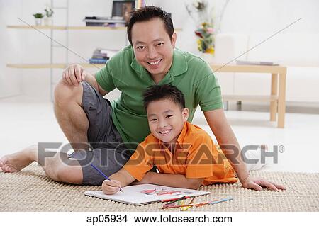 Father and son in living room, smiling at camera, drawing materials around them View Large Photo Image Picture - Father and son in living room, smiling at camera, drawing materials around them. Fotosearch