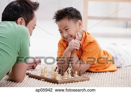 Father and son lying on floor, playing chess, smiling View Large Photo Image Stock Image - Father and son lying on floor, playing chess, smiling. Fotosearch