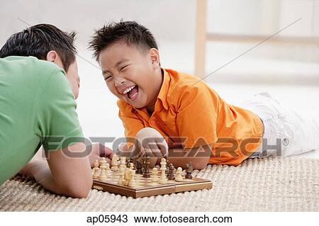 Father and son lying on floor, playing chess, laughing View Large Photo Image Stock Image - Father and son lying on floor, playing chess, laughing. Fotosearch