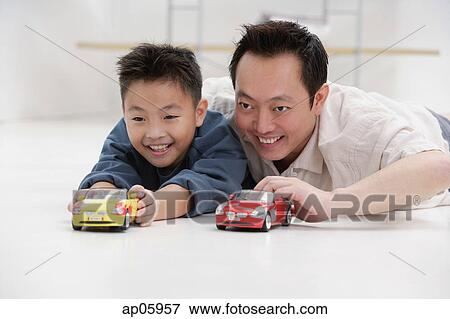 Father and son lying on floor, playing with toy cars View Large Photo Image Stock Photo - Father and son lying on floor, playing with toy cars. Fotosearch