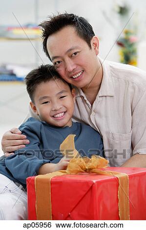 Father and son next to gift box, looking at camera View Large Photo Image Stock Photograph - Father and son next to gift box, looking at camera. Fotosearch