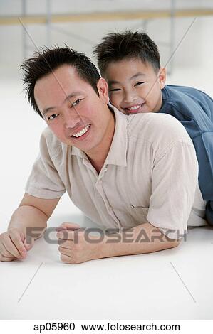 Father lying on floor, son lying on top of him, portrait View Large Photo Image Stock Image - Father lying on floor, son lying on top of him, portrait. Fotosearch