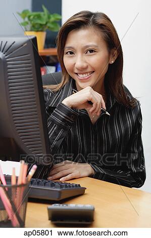 Female executive at desk, hand on chin, smiling at camera View Large Photo Image Stock Image - Female executive at desk, hand on chin, smiling at camera. Fotosearch