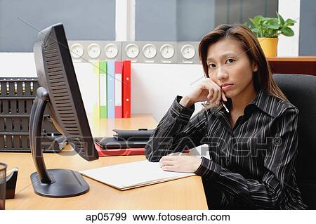 Female executive at desk, hand on chin View Large Photo Image Stock Photo - Female executive at desk, hand on chin. Fotosearch