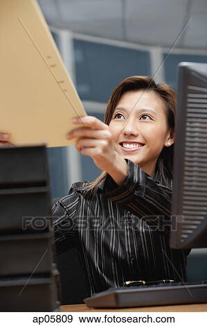 Stock Photo - Female executive handing folder to someone in front of her. Fotosearch