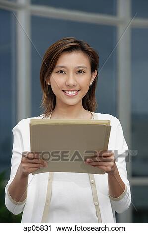 Stock Image - Female executive holding folders towards camera. Fotosearch
