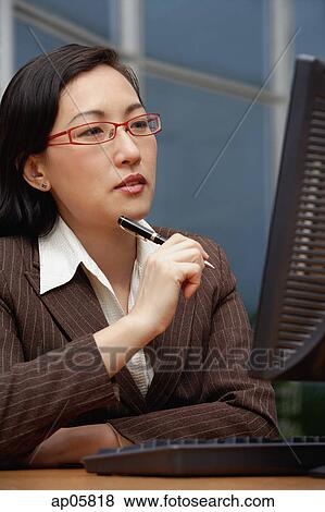 Female executive holding pen, looking at computer monitor View Large Photo Image Stock Photo - Female executive holding pen, looking at computer monitor. Fotosearch