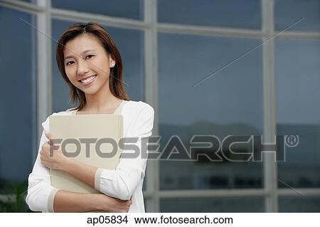 Female executive hugging folders, smiling at camera, portrait View Large Photo Image Picture - Female executive hugging folders, smiling at camera, portrait. Fotosearch