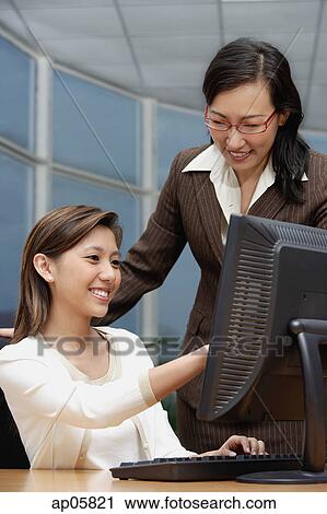 Stock Image - Female executives looking at computer. Fotosearch