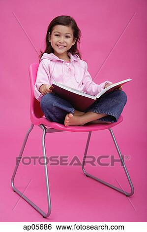 Girl on chair, reading a book, smiling at camera View Large Photo Image Stock Photograph - Girl on chair, reading a book, smiling at camera. Fotosearch