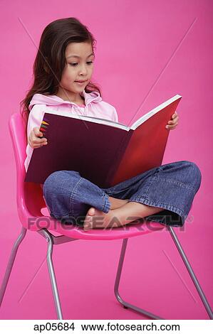 Girl sitting on chair, reading book View Large Photo Image Picture - Girl sitting on chair, reading book. Fotosearch