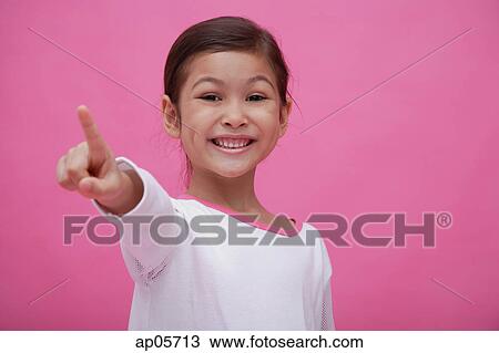 Stock Image - Girl smiling at camera, pointing a finger. Fotosearch