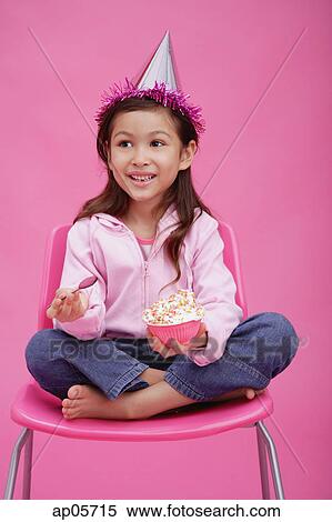 Girl with party hat, sitting on chair, holding bowl of cake View Large Photo Image Stock Photography - Girl with party hat, sitting on chair, holding bowl of cake. Fotosearch