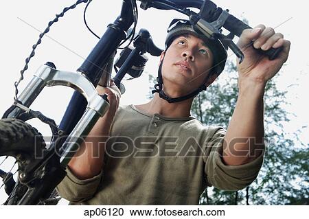 Man carrying bicycle, low angle view View Large Photo Image Stock Image - Man carrying bicycle, low angle view. Fotosearch