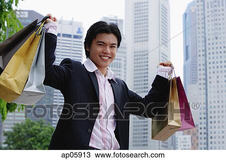 Man carrying shopping bags, smiling at camera View Large Photo Image Stock Image - Man carrying shopping bags, smiling at camera. Fotosearch