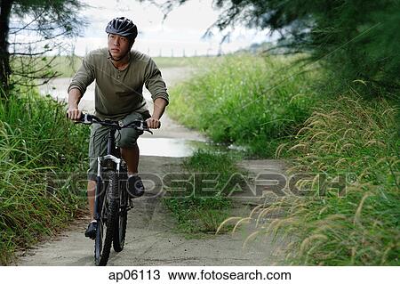 Stock Image - Man cycling on nature path. Fotosearch