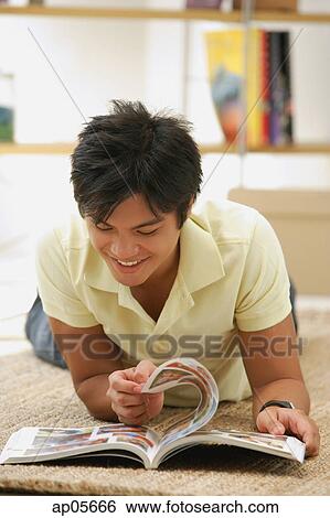 Man flipping through magazine, lying on floor View Large Photo Image Stock Photograph - Man flipping through magazine, lying on floor. Fotosearch