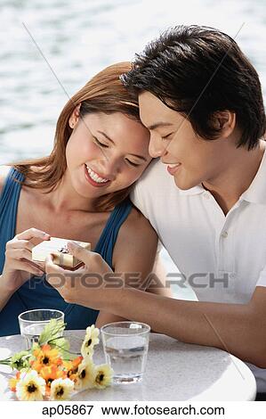Man giving woman a gift box, woman leaning on his shoulder View Large Photo Image Stock Photo - Man giving woman a gift box, woman leaning on his shoulder. Fotosearch