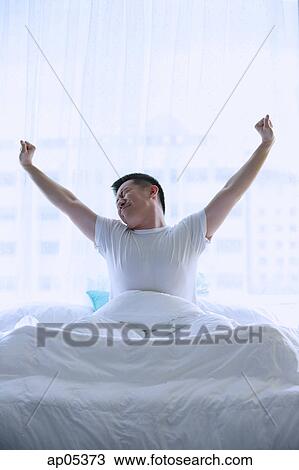 Stock Image - Man in bed, stretching. Fotosearch
