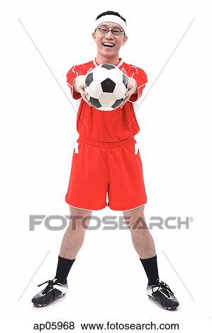 Man in soccer uniform holding soccer ball towards camera View Large Photo Image Stock Photo - Man in soccer uniform holding soccer ball towards camera. Fotosearch