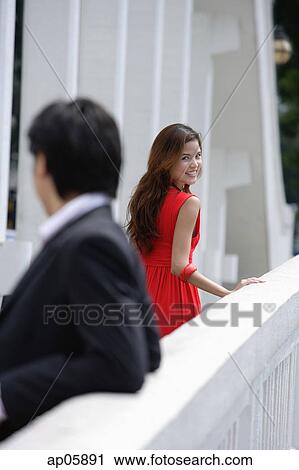 Man leaning on bridge railing, woman in background turning to look at him View Large Photo Image Stock Image - Man leaning on bridge railing, woman in background turning to look at him. Fotosearch