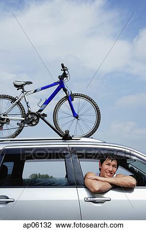 Man leaning out of car window, bicycle on the roof of car View Large Photo Image Stock Image - Man leaning out of car window, bicycle on the roof of car. Fotosearch