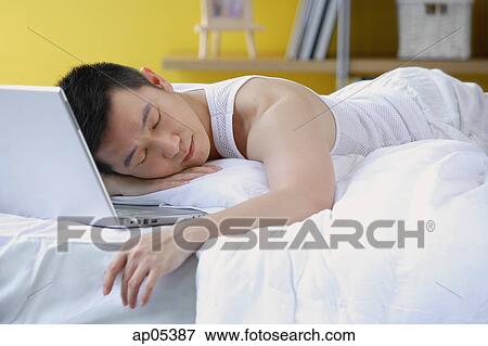 Man lying on bed, sleeping, laptop next to him View Large Photo Image Stock Photo - Man lying on bed, sleeping, laptop next to him. Fotosearch