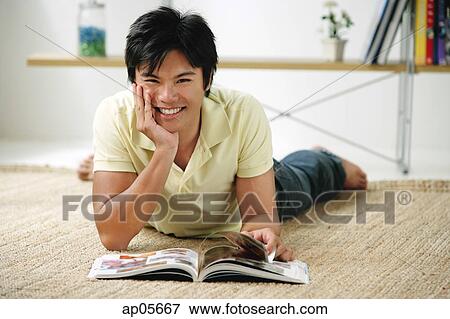 Man lying on floor, hand on chin, smiling at camera View Large Photo Image Stock Photo - Man lying on floor, hand on chin, smiling at camera. Fotosearch