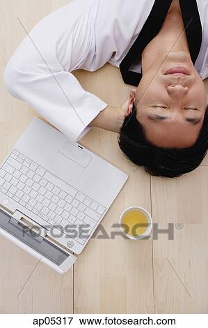 Man lying on floor, hands behind head, laptop next to him View Large Photo Image Stock Photo - Man lying on floor, hands behind head, laptop next to him. Fotosearch