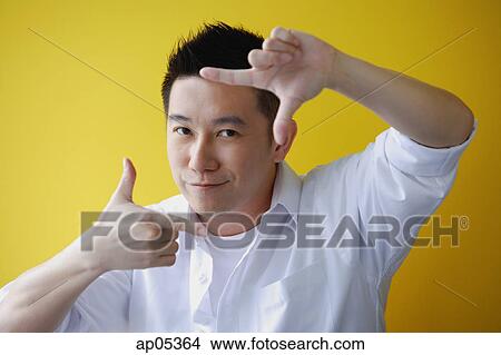 Picture - Man making finger frame, looking at camera. Fotosearch