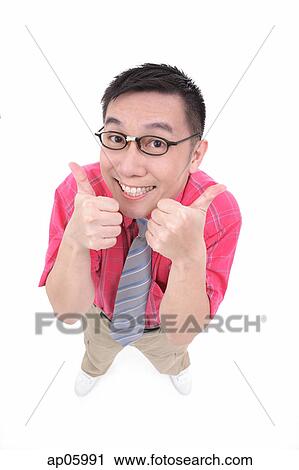 Stock Image - Man making thumbs up sign, smiling at camera. Fotosearch