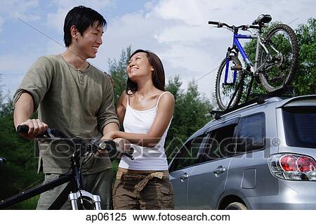 Man on a bike, woman standing next to him, Sports Utility Vehicle in the background View Large Photo Image Stock Photography - Man on a bike, woman standing next to him, Sports Utility Vehicle in the background. Fotosearch