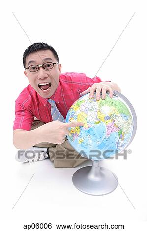Man sitting on floor, pointing to globe, looking at camera View Large Photo Image Stock Photograph - Man sitting on floor, pointing to globe, looking at camera. Fotosearch