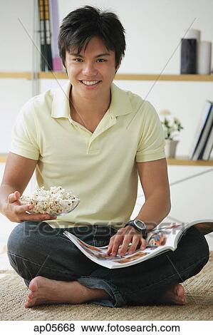 Man sitting on floor, with magazine and bowl of popcorn View Large Photo Image Stock Photo - Man sitting on floor, with magazine and bowl of popcorn. Fotosearch