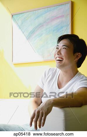 Man sitting on sofa View Large Photo Image Stock Photo - Man sitting on sofa. Fotosearch