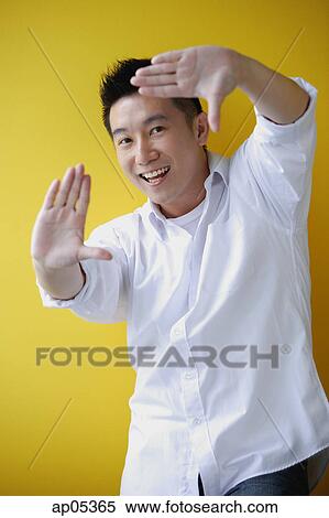 Man smiling at camera, making finger frame View Large Photo Image Stock Photography - Man smiling at camera, making finger frame. Fotosearch