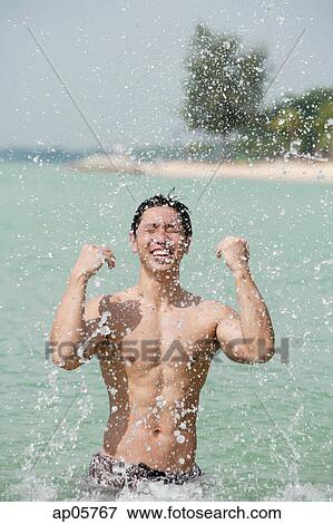 Man standing in sea, splashing water View Large Photo Image Stock Photo - Man standing in sea, splashing water. Fotosearch