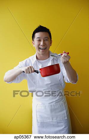 Man wearing apron and holding saucepan View Large Photo Image Stock Photo - Man wearing apron and holding saucepan. Fotosearch