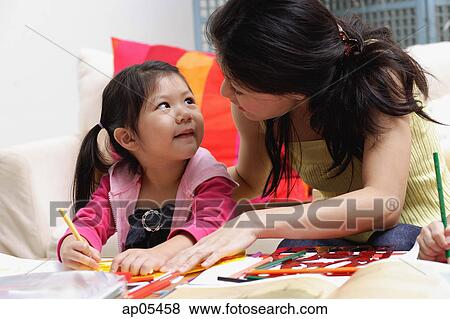 Mother and young daughter drawing at home View Large Photo Image Stock Photo - Mother and young daughter drawing at home. Fotosearch